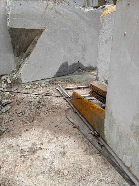 The diamond wire saw on its tracks, the beaded wire looped through the horizontal bores and running around the flywheel for the base cut