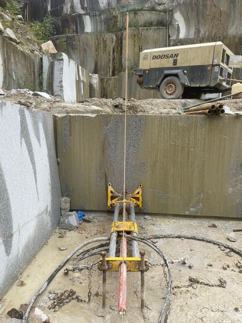 The drill rig set at the foot of the face to bore the first horizontal hole, lined up to meet the vertical bore inside the bench